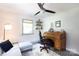 Bright office with a gray sofa, ceiling fan, rolltop desk, and two windows at 3307 Draper Ave, Charlotte, NC 28205