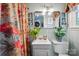 Bright bathroom with a pedestal sink, floral shower curtain, and an above toilet storage cabinet at 404 N Laurel St, Lincolnton, NC 28092