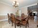 A dining room with traditional wood table, chandelier and paneled wall with easy access to other rooms at 4562 Lanstone Sw Ct, Concord, NC 28027