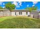 View of the backyard and home featuring a grassy lawn and wood fence at 5648 Woodard St, Charlotte, NC 28269