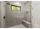Bathroom shower featuring gray subway tile, bench, black hardware, and glass door at 624 Heather Ln, Charlotte, NC 28209