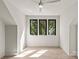 Bright bedroom featuring hardwood floors, ceiling fan, and three large windows at 624 Heather Ln, Charlotte, NC 28209