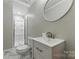 Well-lit bathroom featuring a walk-in shower, white vanity, and round mirror at 7016 Wannamaker Ln, Charlotte, NC 28226