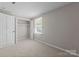 This bedroom features neutral carpeting, a window with blinds, and a closet with bifold doors at 7016 Wannamaker Ln, Charlotte, NC 28226