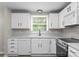 White kitchen cabinets are complemented by a stainless steel stove and wood look floor at 7016 Wannamaker Ln, Charlotte, NC 28226
