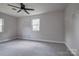 Well-lit bedroom features a ceiling fan, plush gray carpet, and two windows at 85 Sw Myrtle Sw Ave, Concord, NC 28025