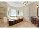 Elegant bathroom featuring a soaking tub with tiled surround and decorative lighting at 8904 Woodhall Lake Dr, Waxhaw, NC 28173