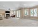Open living room features a fireplace, ceiling fan, carpeted floor, and multiple windows for bright light at 8904 Woodhall Lake Dr, Waxhaw, NC 28173