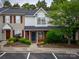 Charming townhouse featuring a brick facade, blue door, manicured landscaping, and red shutters at 118 Barnhardt Loop, Mooresville, NC 28117