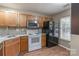 Kitchen with wood cabinets, granite countertops, black appliances and wood-look flooring at 118 Barnhardt Loop, Mooresville, NC 28117
