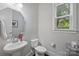 Neat powder room with a pedestal sink, toilet, and mirrored cabinet, illuminated by natural light at 1209 Leigh Ave, Charlotte, NC 28205
