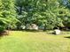 A grassy backyard featuring mature trees, a storage shed, and a grill at 1750 Sells Rd, Salisbury, NC 28144