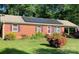 Charming brick home featuring solar panels, colorful shutters, a metal roof, and a well-maintained front yard at 1750 Sells Rd, Salisbury, NC 28144