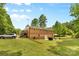 Back exterior of a brick home with a patio and deck overlooking a well-maintained lawn and a lush, wooded landscape at 1792 Hoffman Rd, Gastonia, NC 28054