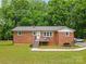 Charming brick home featuring a metal roof, cozy front porch, and well-maintained lawn at 1792 Hoffman Rd, Gastonia, NC 28054