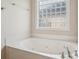 Bathroom featuring soaking tub with tile surround and glass block window at 2910 Lake James Ct, Monroe, NC 28110