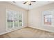 This bedroom features neutral carpet, two windows with blinds, a ceiling fan, and a 'For Sale' sign on the floor at 2910 Lake James Ct, Monroe, NC 28110