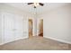 This bedroom features neutral carpet, a ceiling fan, closet, and a doorway to the bathroom at 2910 Lake James Ct, Monroe, NC 28110