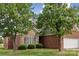 View of the brick and stone facade with dark shutters, manicured lawn, and trees at 2910 Lake James Ct, Monroe, NC 28110