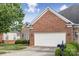 View of the brick and stone facade, and an attached two-car garage with mailboxes, and a well-manicured lawn at 2910 Lake James Ct, Monroe, NC 28110