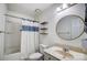 Bathroom featuring a shower with patterned curtain, three wooden shelves, and a round mirror at 3109 Heathstead Pl, Charlotte, NC 28210