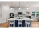 Well-lit kitchen with white cabinets, stainless steel appliances, and center island with bar stools at 4040 Deep River Way, Waxhaw, NC 28173