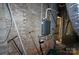 Unfinished basement showing water heater with brick walls and some clutter at 5127 Murrayhill Rd, Charlotte, NC 28210