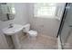 Well-lit bathroom with a pedestal sink, toilet, shower with window, and tile flooring at 5127 Murrayhill Rd, Charlotte, NC 28210
