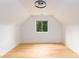 Bright attic featuring hardwood floors, a central window offering natural light, and neutral walls for versatile use at 6501 Piney Path Rd, Charlotte, NC 28212