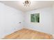 Bright bedroom showcasing hardwood floors, a large window, double closet with black handles, and modern lighting at 6501 Piney Path Rd, Charlotte, NC 28212