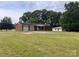 View of the brick home, two-car garage, out-building, and surrounding green lawn at 675 E Ritchie Rd, Salisbury, NC 28146
