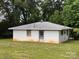 Single story home with a white brick exterior, simple design, and set in a large, green yard surrounded by trees at 675 E Ritchie Rd, Salisbury, NC 28146