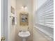 Charming powder room featuring a pedestal sink, decorative mirror, and window with blinds, offering a bright and inviting space at 6909 Dunton St, Huntersville, NC 28078