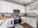 Detailed view of the kitchen with stainless steel oven, microwave, and white cabinetry, creating a clean and modern cooking space at 6909 Dunton St, Huntersville, NC 28078