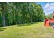 A verdant lawn leads up to a wooded property line behind a charming brick home at 707 Hester Dr, Dallas, NC 28034