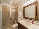 Well-lit bathroom featuring a glass-enclosed shower and a decorative mirror over the sink at 7138 Wessynton Dr, Charlotte, NC 28226