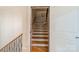 View of wooden stairs with white risers and a dark metal railing through a doorway at 7138 Wessynton Dr, Charlotte, NC 28226
