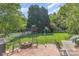 A spacious backyard with a brick patio, fire pit, playset, lush lawn, and mature trees at 815 Clearbrook Rd, Matthews, NC 28105