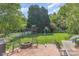 A spacious backyard with a brick patio, fire pit, playset, lush lawn, and mature trees at 815 Clearbrook Rd, Matthews, NC 28105