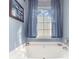 Bathroom featuring a soaking tub with blue accents and a window at 815 Clearbrook Rd, Matthews, NC 28105