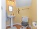 Small bathroom with pedestal sink, toilet, and yellow painted walls at 815 Clearbrook Rd, Matthews, NC 28105