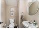 Neutral powder room features a round mirror, decorative artwork, and a toilet at 8734 Meadowmont View Dr, Charlotte, NC 28269
