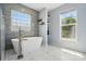 Serene bathroom featuring a soaking tub, marble floors, and natural light at 8833 Cavonnier Ln, Charlotte, NC 28216