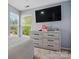 Bright bedroom with a large flat screen television, neutral colored dresser, and natural light from the windows at 8833 Cavonnier Ln, Charlotte, NC 28216