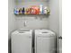 Modern laundry room featuring a white front-load washer and dryer with storage shelf above at 8833 Cavonnier Ln, Charlotte, NC 28216