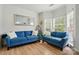 Cozy living room with ample natural light, featuring two blue couches and hardwood floors at 8833 Cavonnier Ln, Charlotte, NC 28216