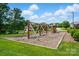 Community playground with swings, slides, and climbing structures, surrounded by grass and trees at 8833 Cavonnier Ln, Charlotte, NC 28216