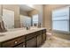 Bright bathroom featuring a large mirror, vanity with dark cabinets, and a shower with tiled accents at 1026 Slew O Gold Ln, Indian Trail, NC 28079