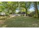 A spacious backyard features a well-maintained lawn, mature trees and a view of the home's rear at 115 W 5Th Ave, Gastonia, NC 28052