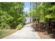 Long concrete driveway leading to a white farmhouse, surrounded by mature trees and landscaping at 16432 Here At Last Ln, Charlotte, NC 28278